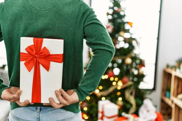 Young Redhead Man Holding Gift Back Standing Christmas Tree Home — Stock Photo, Image