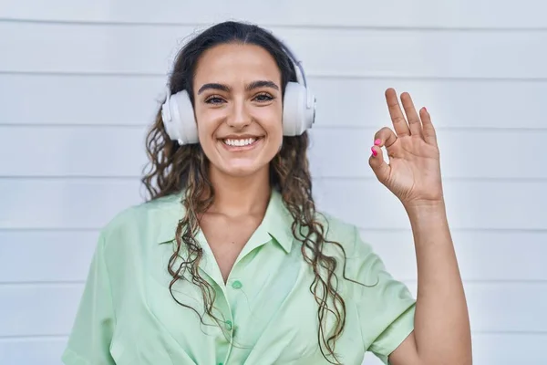 Young Hispanic Woman Listening Music Using Headphones Doing Sign Fingers — Foto Stock