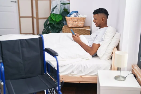 Young Latin Man Using Smartphone Lying Bed Bedroom — Stok fotoğraf