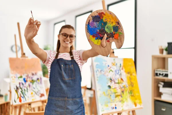 Mujer Joven Sonriendo Confiada Sosteniendo Pincel Paleta Estudio Arte — Foto de Stock