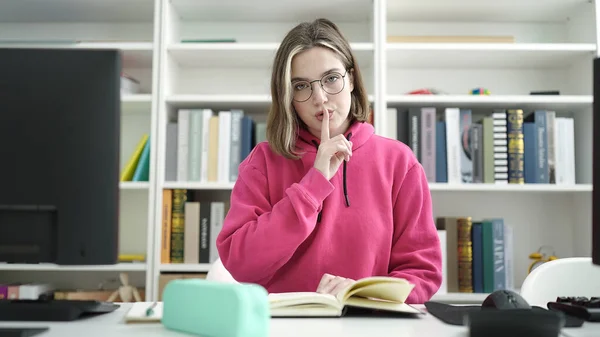 Young Blonde Woman Student Reading Book Doing Silence Gesture Library — Foto de Stock