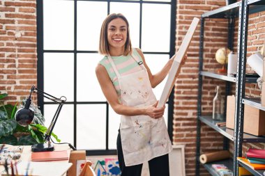 Young beautiful hispanic woman artist smiling confident holding draw at art studio