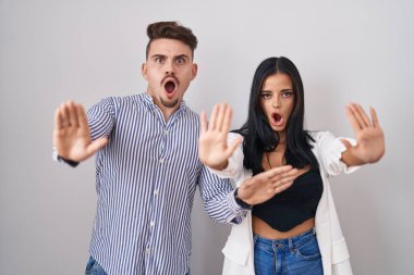 Beyaz arka planda duran genç İspanyol çift avuç içi hareketlerini durduruyorlar, kızgın ve hayal kırıklığına uğramış bir ifade. 