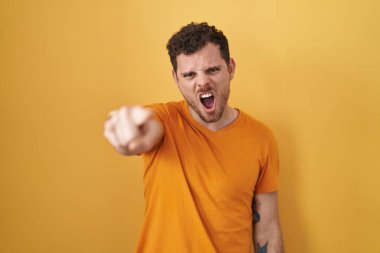 Sarı arka planda dikilen Latin asıllı genç adam kameraya kızgın ve sinirli olduğunu gösteriyor. 