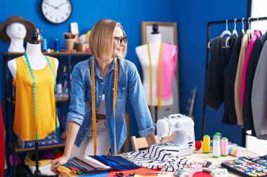 Young blonde woman tailor smiling confident standing at sewing studio