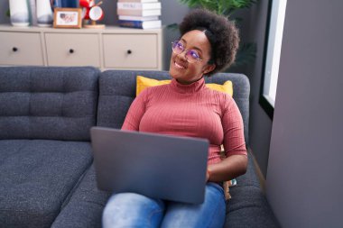 African american woman using laptop sitting on sofa at home