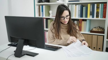 Kütüphanedeki bilgisayar okuma belgesini kullanan güzel İspanyol kadın öğrenci.