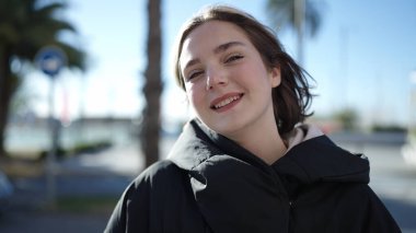 Parkta kendinden emin gülümseyen genç sarışın kadın.