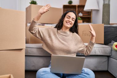 Genç İspanyol kadın yeni evinde dizüstü bilgisayar kullanıyor.