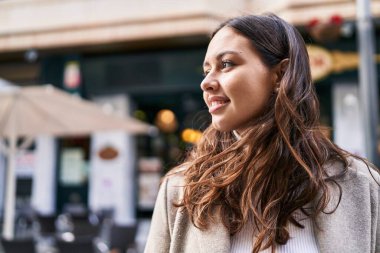 Young beautiful hispanic woman smiling confident looking to the side at street