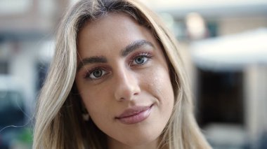 Sokakta ciddi bir ifadeyle duran genç sarışın kadın.