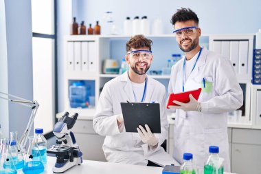 Young couple wearing scientist uniform using touchpad at laboratory