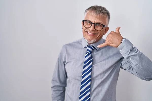 灰色の髪をしたヒスパニック系のビジネスマンは 電話で話すような手や指で携帯電話のジェスチャーを行う笑顔眼鏡を着用しています コミュニケーションの概念 — ストック写真