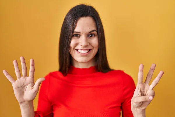 Молода Іспаномовна Жінка Стоїть Над Жовтим Тлом Показуючи Вказуючи Пальцями — стокове фото