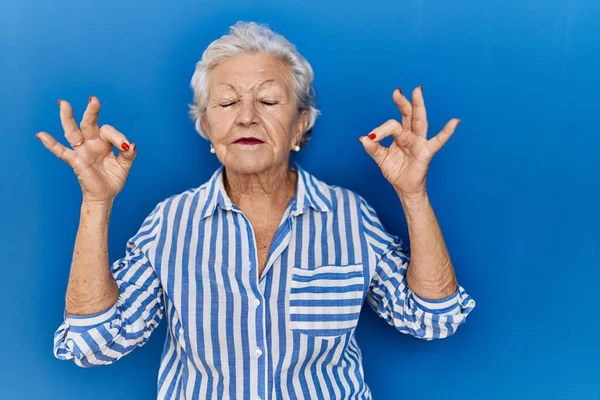 Mavi Arka Planda Duran Gri Saçlı Yaşlı Kadın Rahatla Parmaklarıyla — Stok fotoğraf