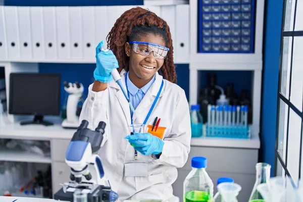 アフリカ系アメリカ人女性科学者が実験室で試験管に液体を注ぐ — ストック写真