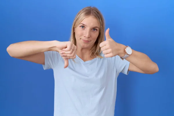 stock image Young caucasian woman wearing casual blue t shirt doing thumbs up and down, disagreement and agreement expression. crazy conflict 