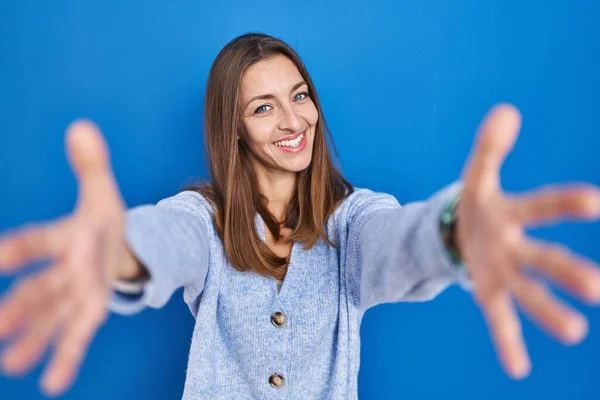Young Woman Standing Blue Background Looking Camera Smiling Open Arms — Fotografia de Stock