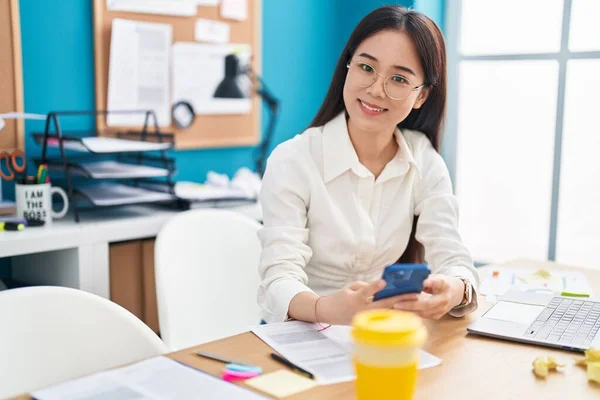 オフィスで働くスマートフォンを利用した若い中国人女性ビジネスワーカー — ストック写真