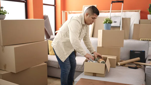 Young Hispanic Man Unpacking Cardboard Box New Home — Fotografia de Stock