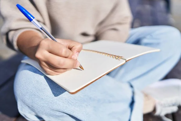 通りのベンチに座ってノートを書く若い女性 — ストック写真
