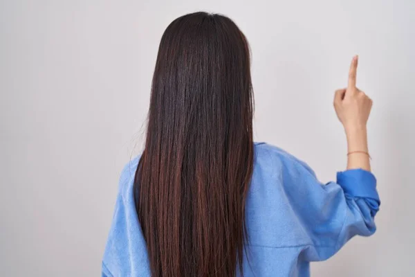 年轻的中国女人站在白种人的背景上 手指头朝前看去 — 图库照片