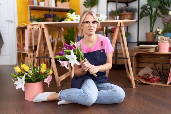 床の無慈悲で混乱した表情の花屋で働く若い白人女性 疑わしい概念 — ストック写真