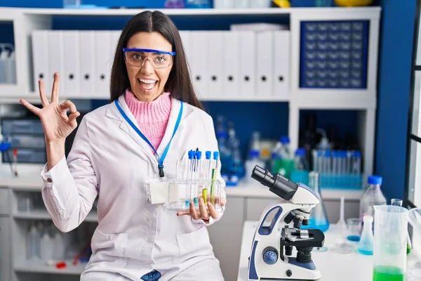 Young Brunette Woman Working Scientist Laboratory Doing Sign Fingers Smiling — Zdjęcie stockowe