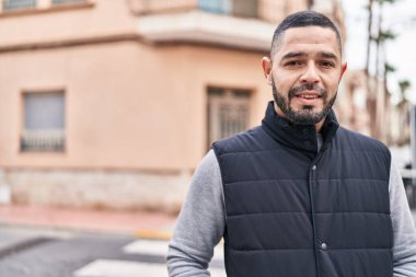 Young latin man smiling confident standing at street