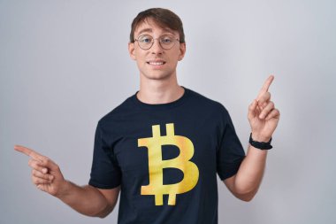 Bitcoin tişörtü giyen beyaz, sarışın, kendine güvenen, farklı yönleri gösteren bir adam. reklam için kopyalama alanı 