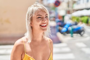 Young blonde woman smiling confident looking to the side at street