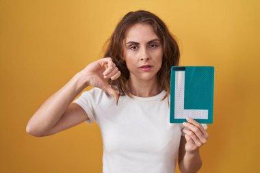 Güzel esmer bir kadın tutuyor. Kızgın yüzlü yeni bir sürücü için imza atıyorum. Negatif işaretler baş parmakları aşağıda, reddedilme konsepti ise reddedilme. 