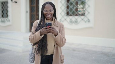 African woman smiling using smartphone at street