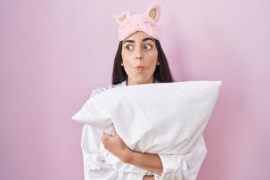 Genç esmer kadın uyku maskesi takmış, pijama giymiş, yastığa sarılıyor, balık suratlı, şaşı gözlü, çılgın ve komik.. 