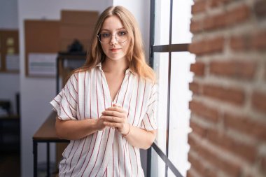 Genç sarışın iş kadını ofiste kendinden emin duruyor.