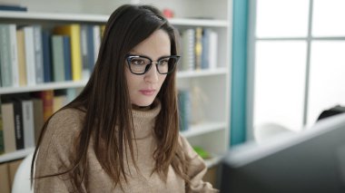 Güzel İspanyol kadın öğrenci kütüphane üniversitesinde bilgisayar kullanıyor.