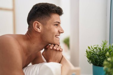 Genç İspanyol adam yatakta kendinden emin bir şekilde gülümsüyor.