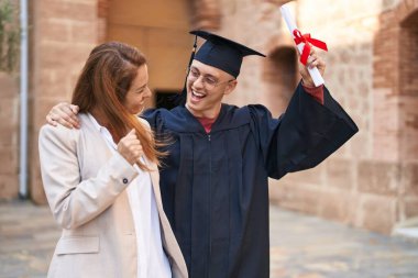 Man and woman mother and son hugging each other celebrating graduation at university