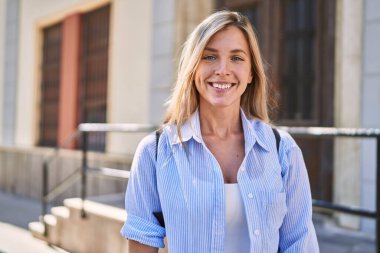 Sokakta kendine güvenen genç sarışın kadın gülümsüyor