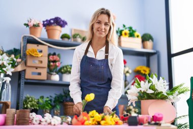 Young blonde woman florist make bouquet of flowers at florist