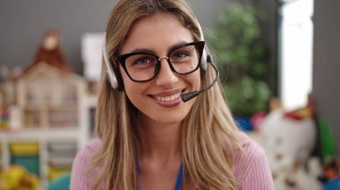 Young blonde woman teacher smiling confident having video call at kindergarten