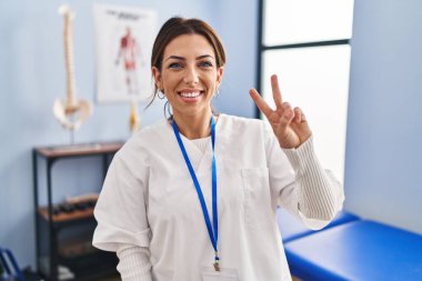 Ağrı kesici kliniğinde çalışan genç esmer kadın kameraya bakıp zafer işareti yaparken gülümsüyor. İki numara.. 