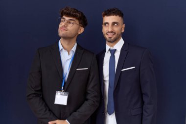 İki İspanyol iş adamı iş kıyafetleri giymiş gülümseyip yan tarafa bakıyor ve düşünüyor.. 