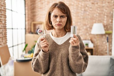 Genç, güzel bir kadın elinde ampul ve parlak bir ampul tutuyordu. Depresyondaydı ve sıkıntıdan endişe ediyordu. Öfkeli ve korkmuştu. hüzünlü ifade. 