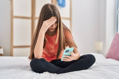 Yatak odasında akıllı telefon kullanan sevimli bir kız.