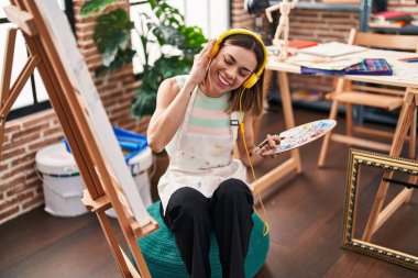 Sanat stüdyosunda müzik dinleyen genç, güzel İspanyol kadın sanatçı.