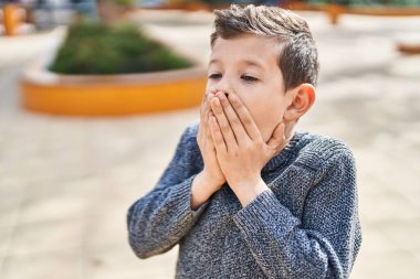 Sarışın çocuk parkta hazırlıksız duruyor.