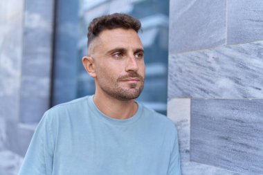 Latin kökenli genç adam ciddi bir ifadeyle sokağa bakıyor.