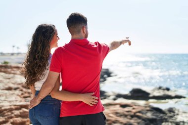 Genç İspanyol turistler deniz kenarında birbirlerine sarılıyorlar.