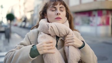 Sokakta soğuk hava için fular takan beyaz bir kadın.